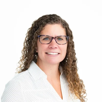 Kristen smiling in front of a white wall.