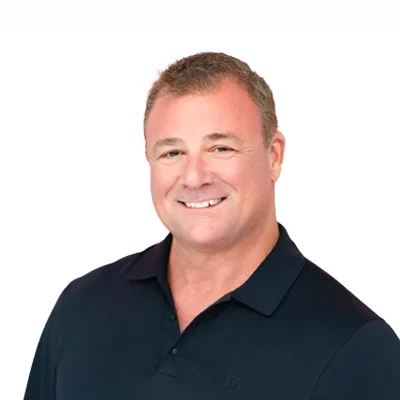 Michael Simmer smiling in front of a white wall.