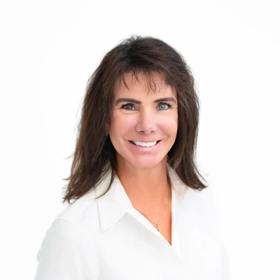 Shaun Simmer smiling in front of a white wall.