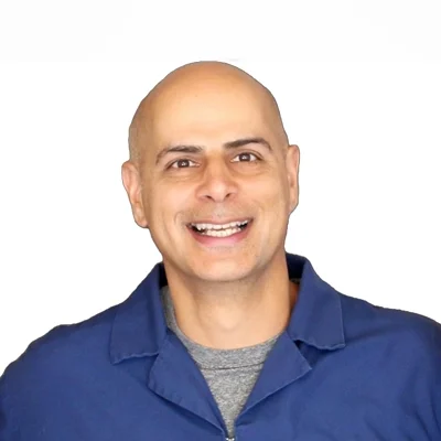 Syd Dhillon smiling in front of a white wall.